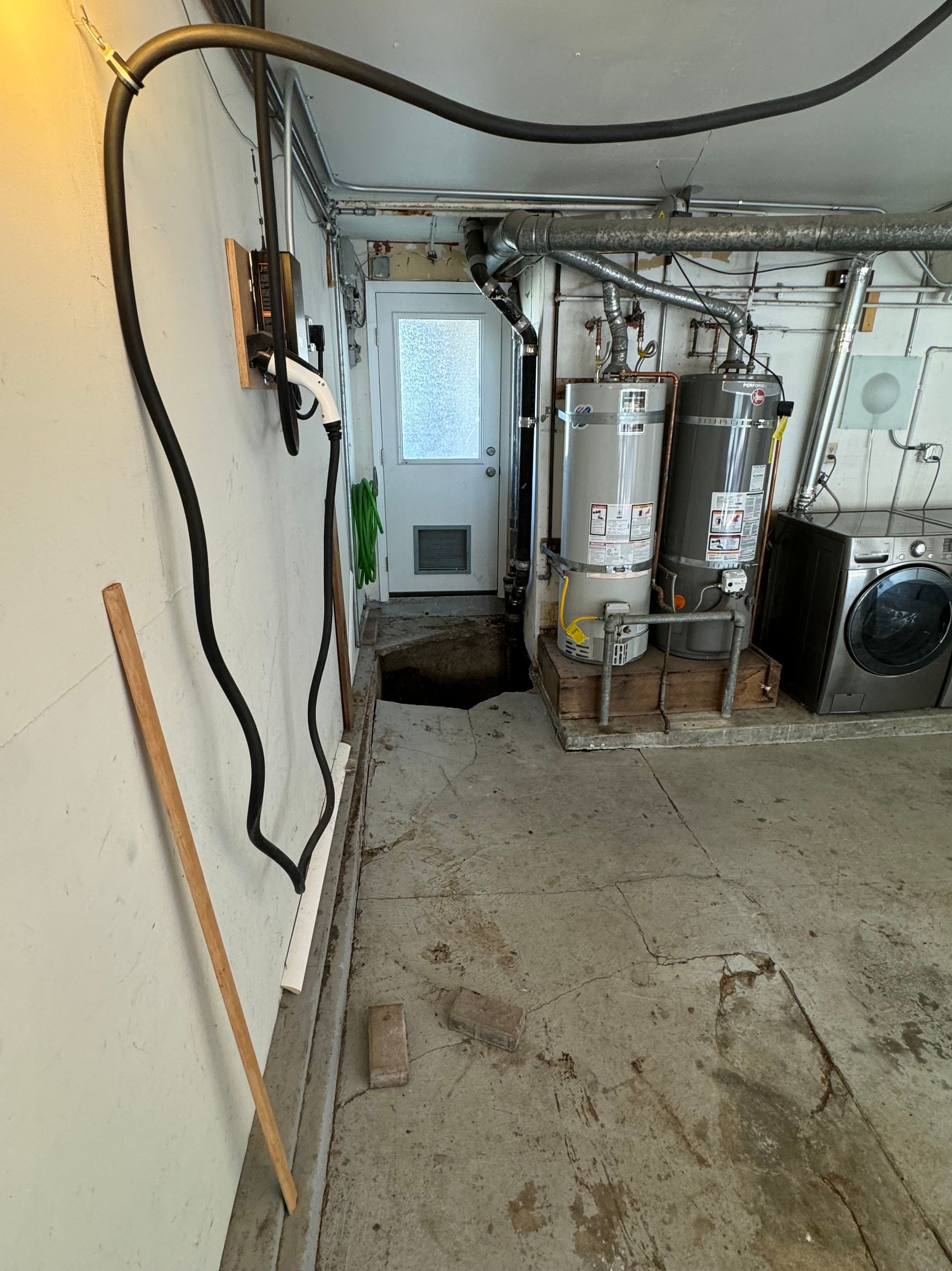 Basement utility room with pipes, water heater, electrical box, and concrete floor.