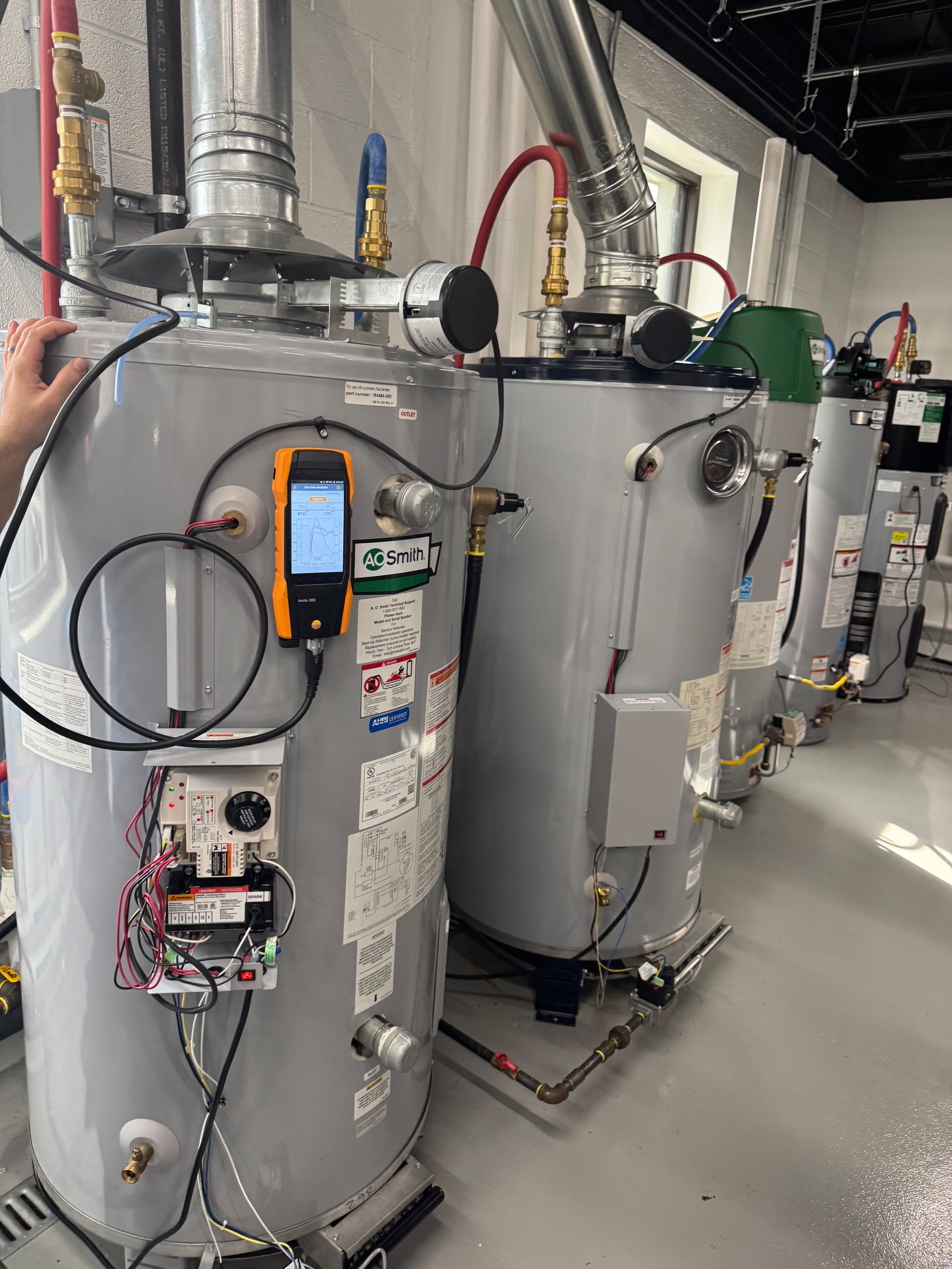 Industrial water tanks and pipes in a mechanical room, with control panels and gauges on large metal cylinders.