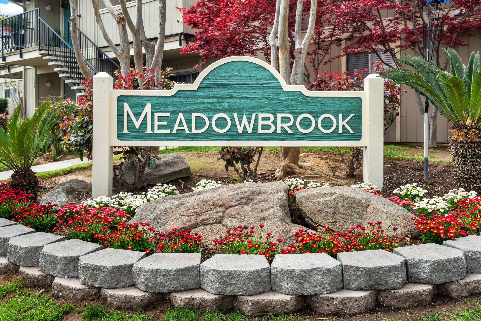 Sign for Meadowbrook apartment complex with landscaping and flowers.