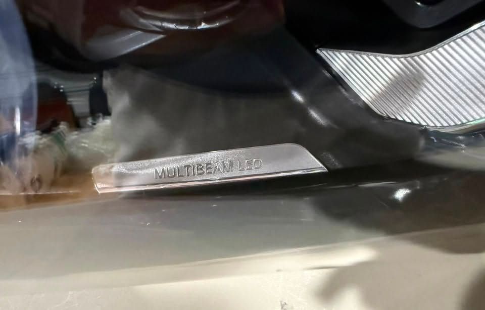 Close-up of a shiny metal nameplate on a dark surface with blurred reflections above it