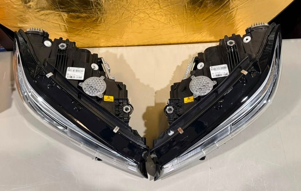 Two black car headlight assemblies side by side on a light background