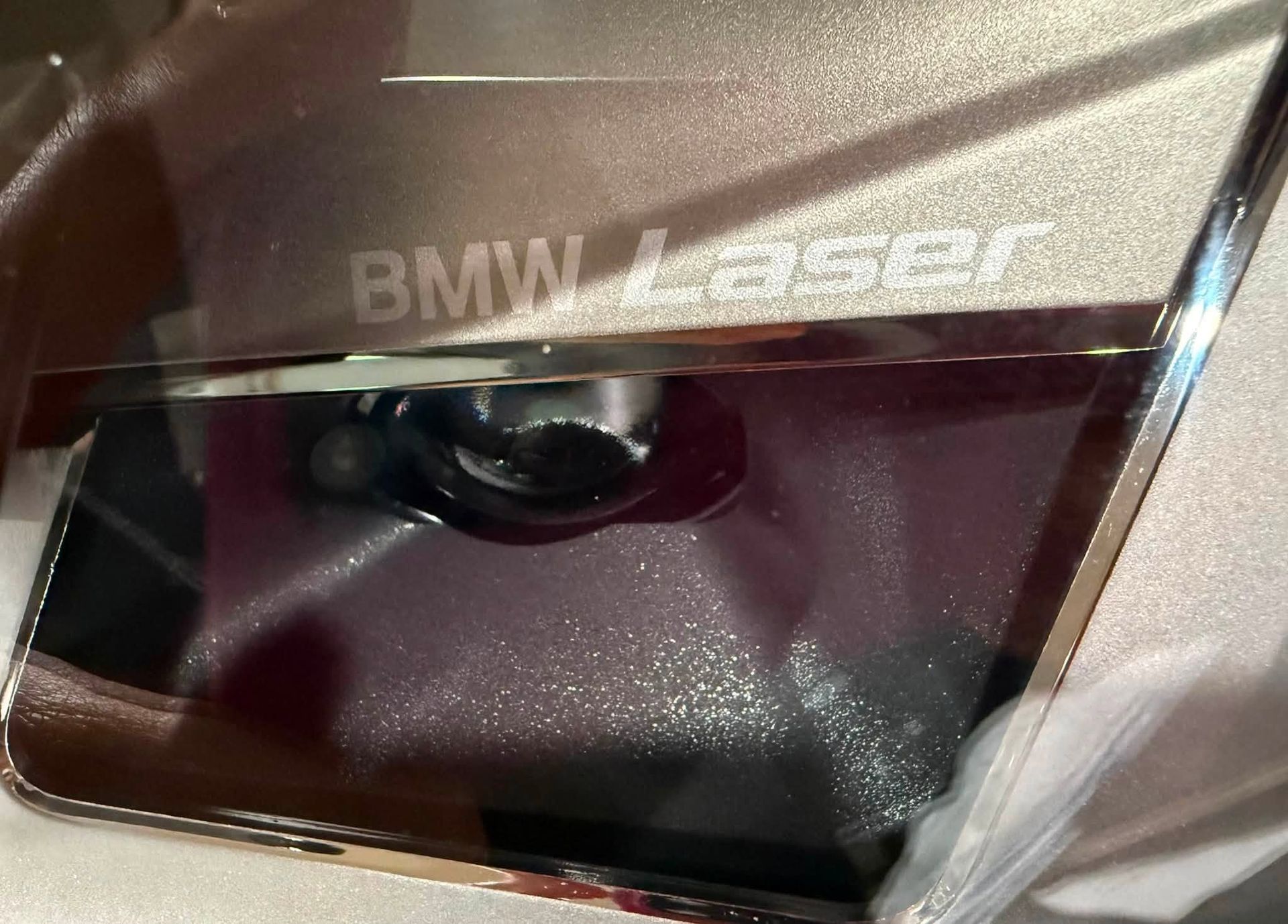 Close-up of a BMW Laser headlight lens with reflective silver trim.