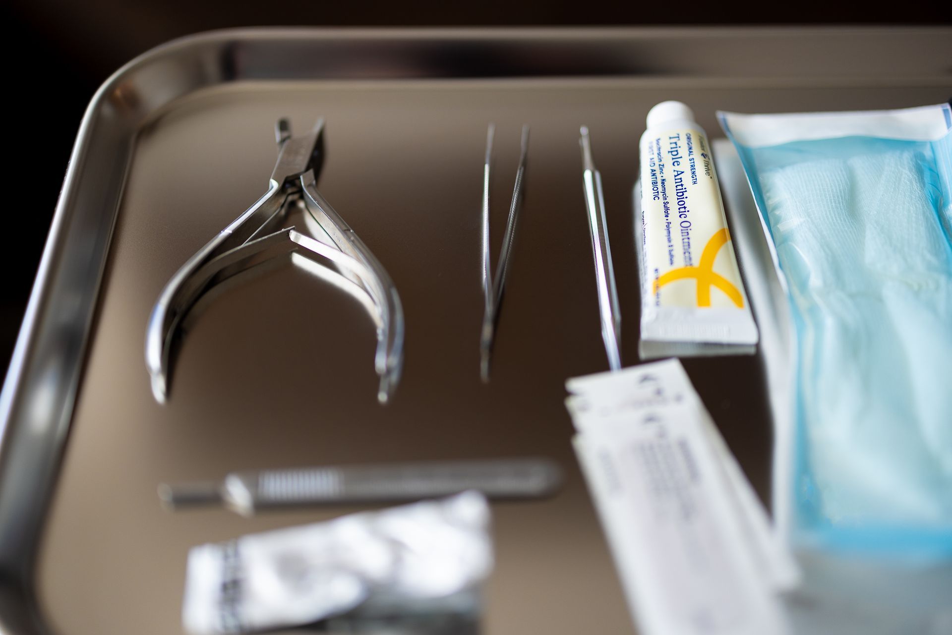 Dental tools and supplies arranged on a tray, including pliers, tweezers, and a syringe.