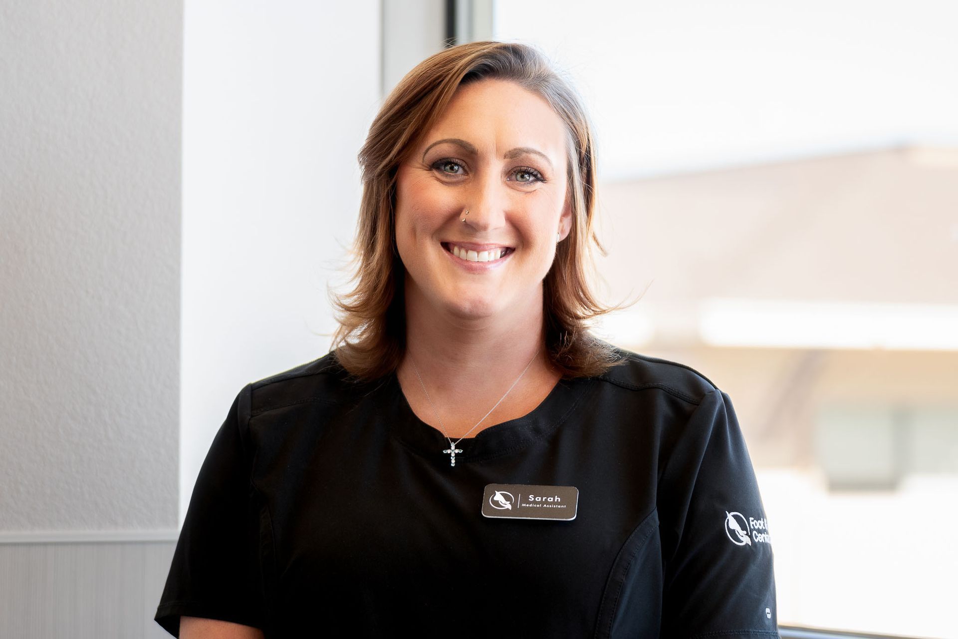 Maritza a medical assistant in a black shirt is standing with her arms crossed.