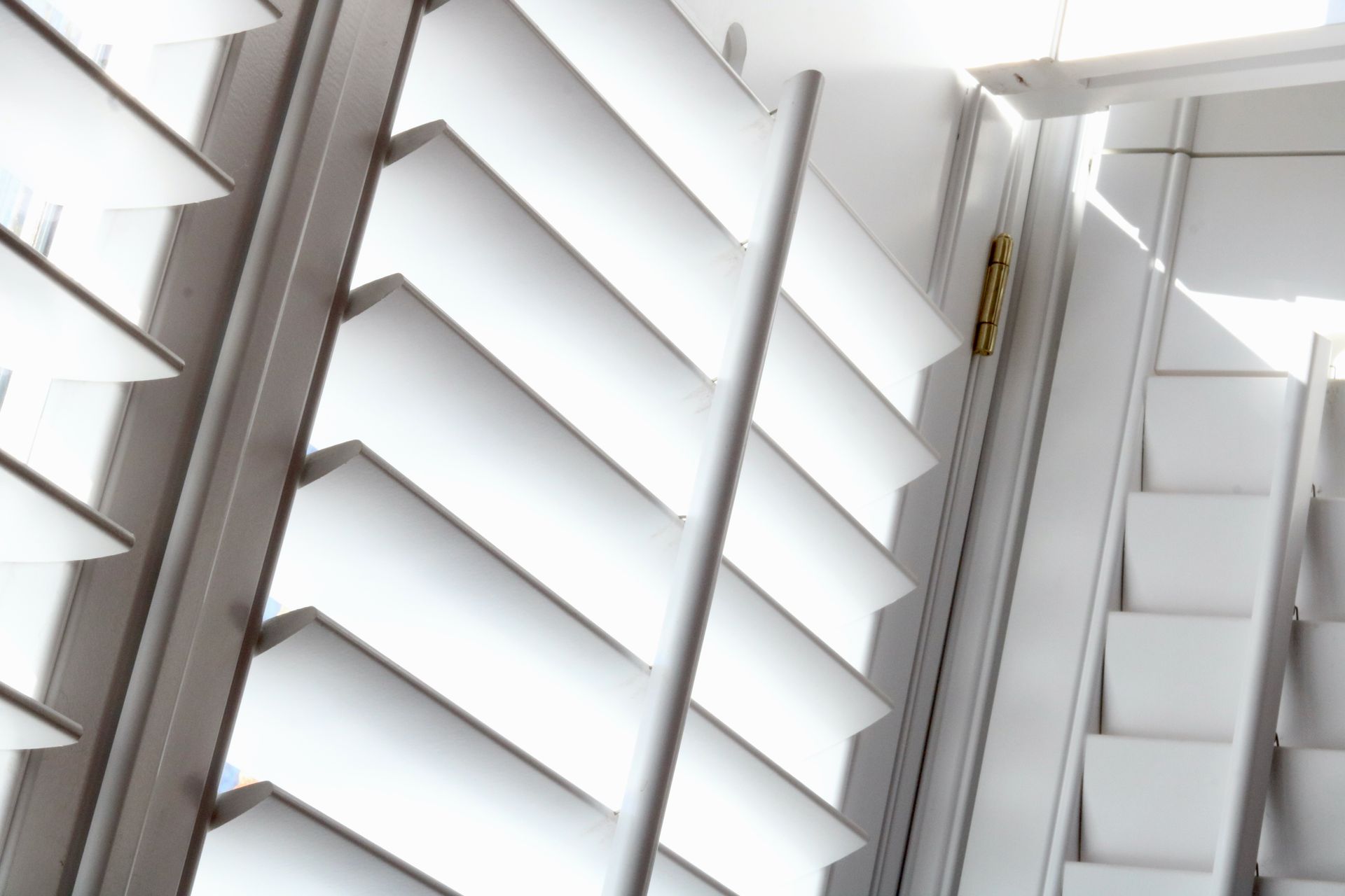 Angled full-frame image of light shining through plantation shutters.