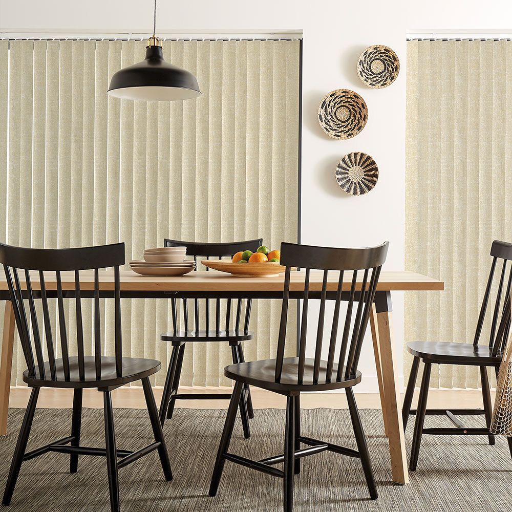 Dining room with a wooden table and black chairs, vertical blinds.