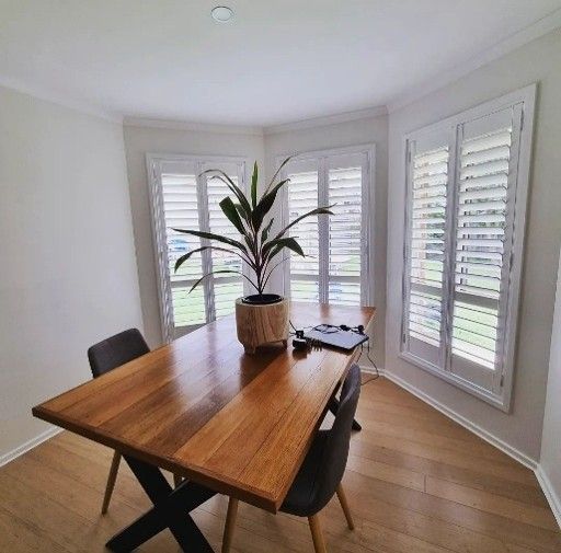 Photograph of a minimalist dining area featuring a rectangular wooden table with black metal legs, s