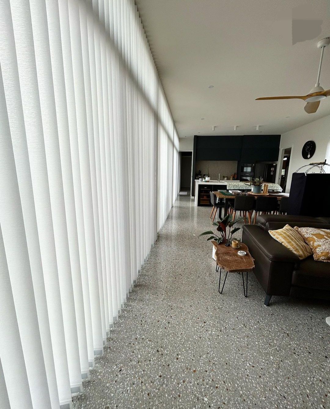 White vertical blinds cover a long window.