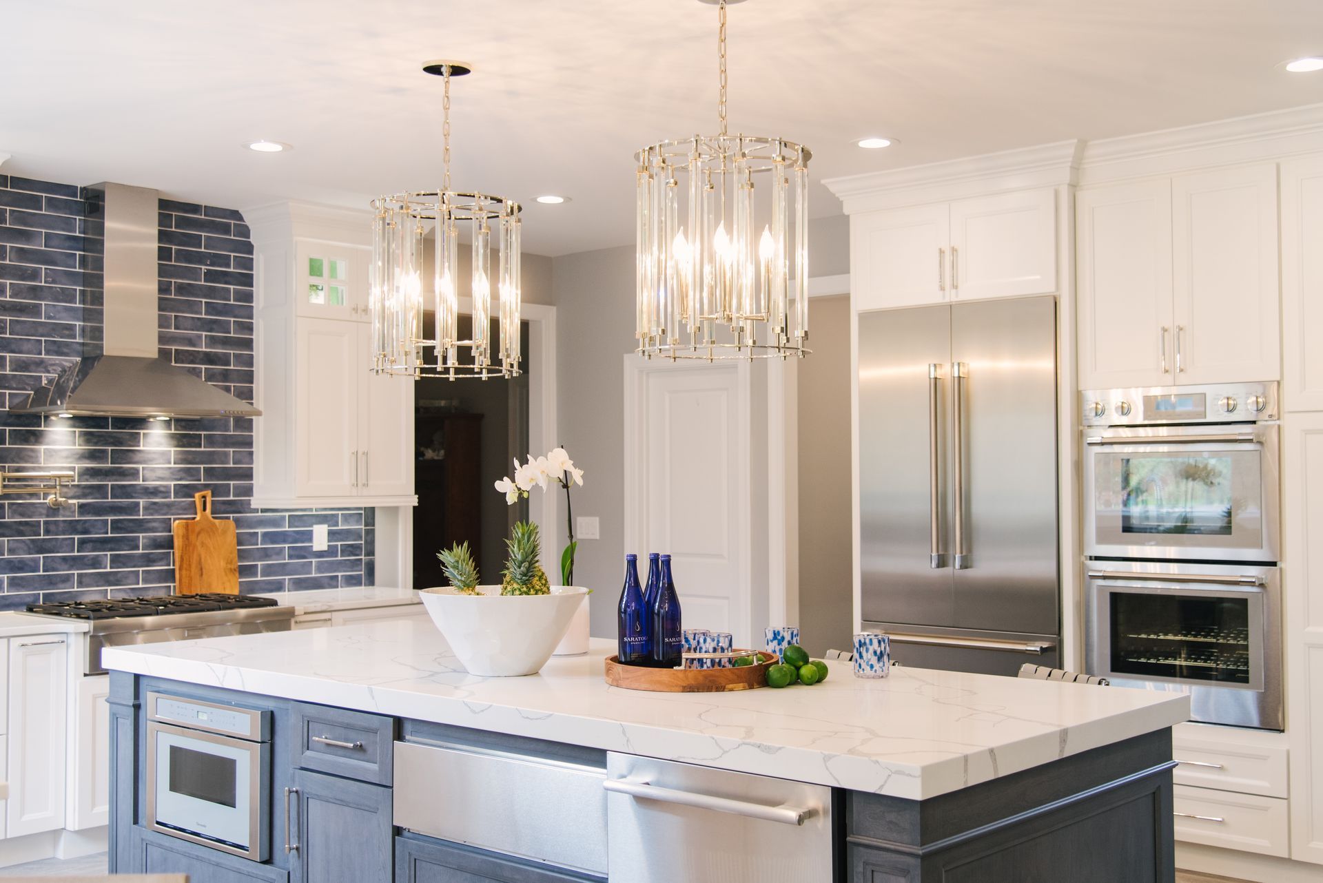 A kitchen with white cabinets , stainless steel appliances , and a large island.