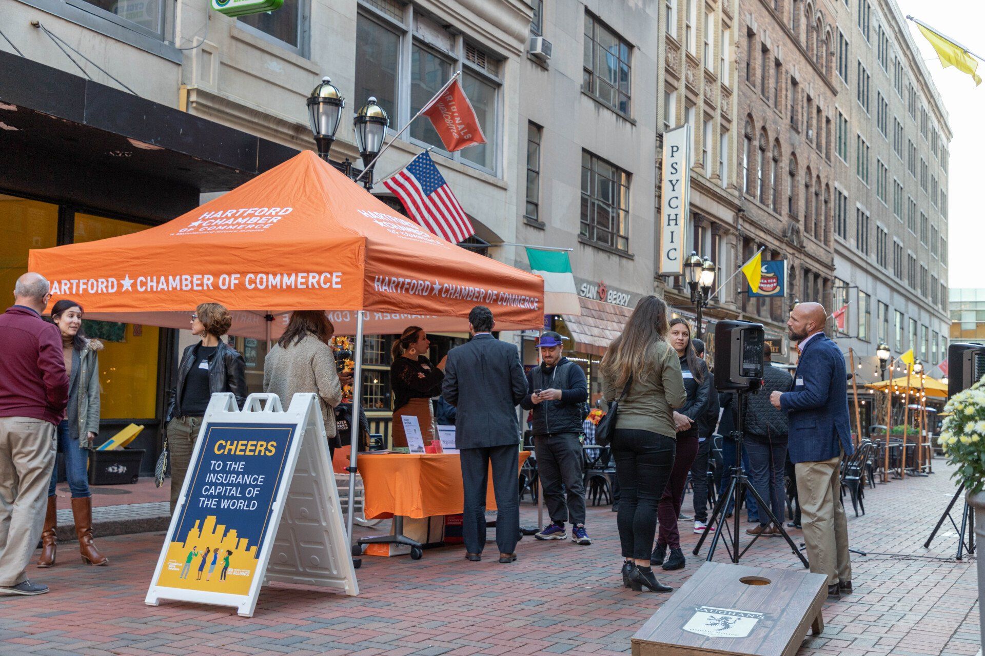 A group of people are standing under an orange tent on a city street.