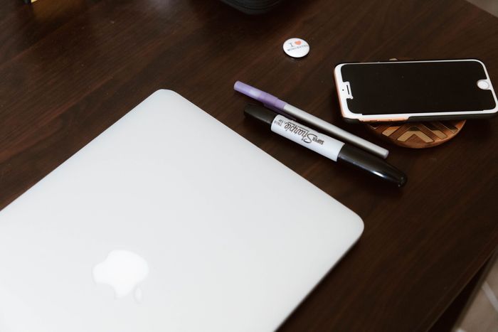 A sharpie marker sits on a table next to a laptop