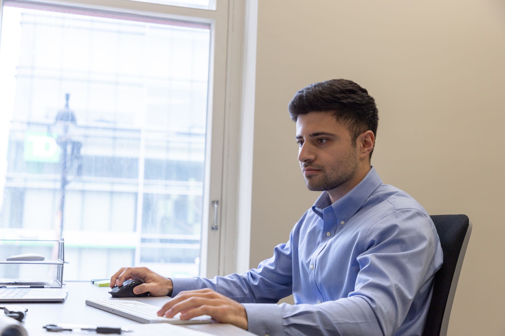 A man is sitting at a desk typing on a laptop computer.