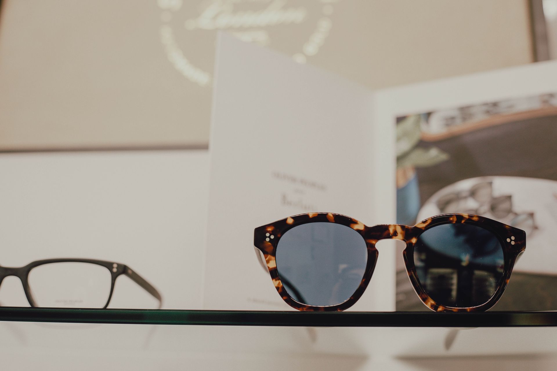 A pair of sunglasses and a pair of glasses are sitting on a shelf.