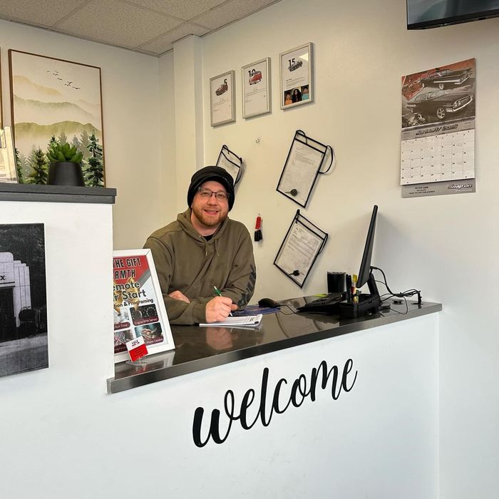 A man sits behind a counter that says welcome | Value Service Center