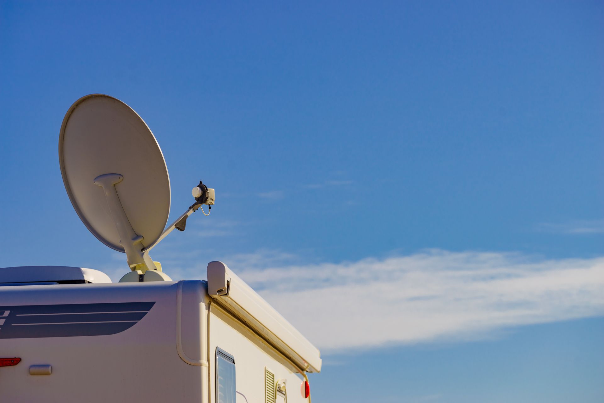 White RV with satellite dish against a blue sky. White RV with satellite dish against a blue sky.