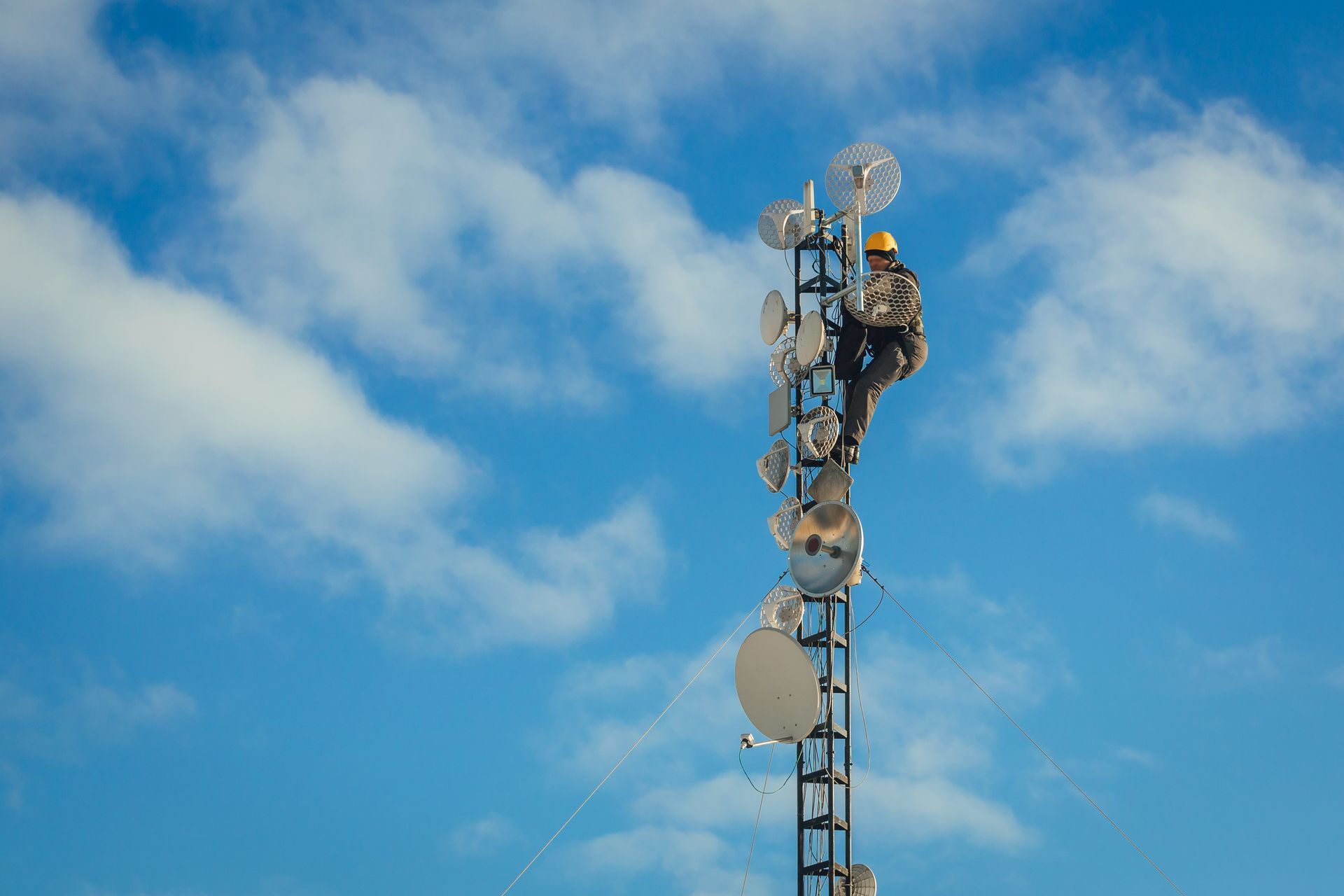 Worker on a communications tower, blue sky, clouds. Worker on a communications tower, blue sky, clouds.