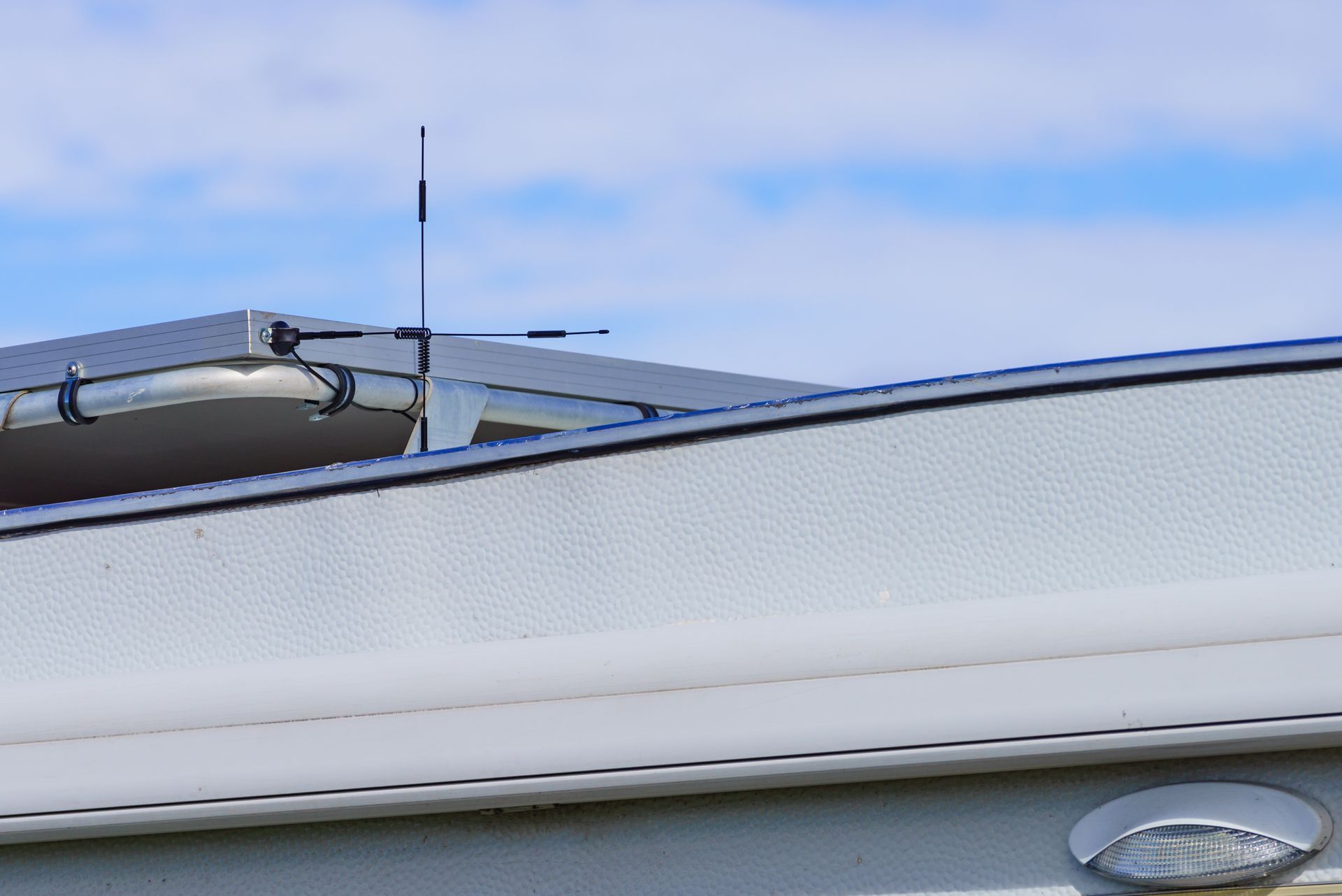 White RV with antenna on roof against a blue and cloudy sky. White RV with antenna on roof against a blue and cloudy sky.