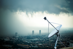 Satellite dish overlooking a city on a cloudy day. Satellite dish overlooking a city on a cloudy day.