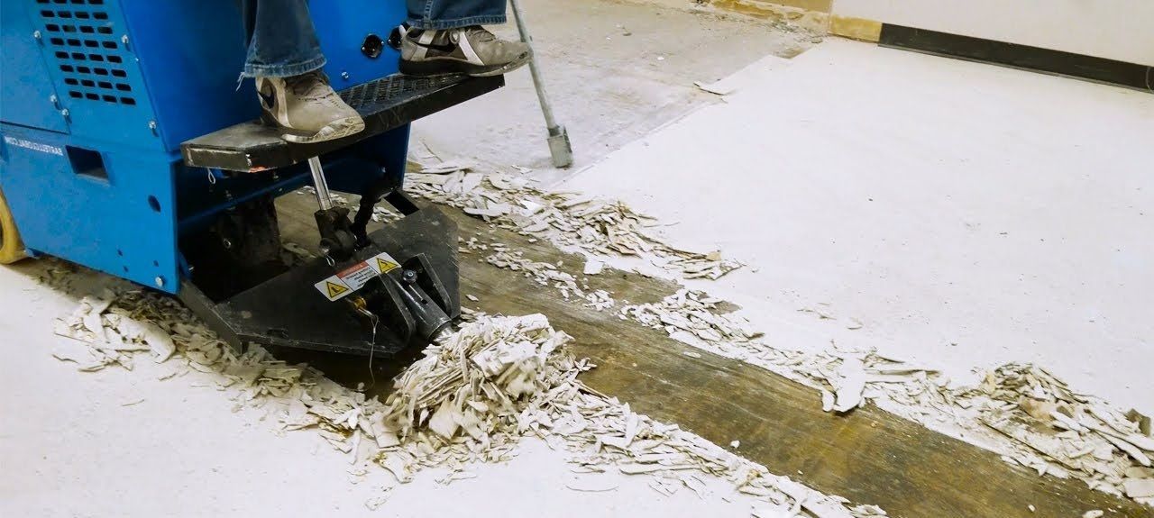 Blue machine spreading wet concrete over a white floor surface