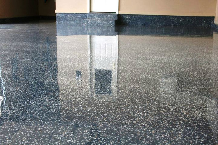 Polished speckled floor reflecting a wall and doorway in an indoor hallway