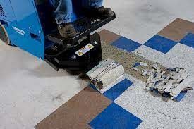 Floor scrubber cleaning up spilled white paper on a blue-and-brown tiled floor