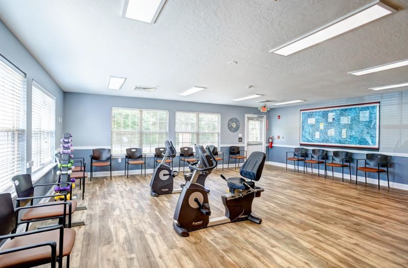 A large room with exercise bikes and chairs in it.