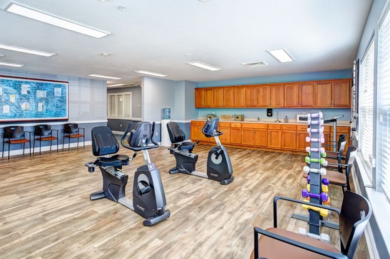 A large room with exercise bikes and dumbbells in it.