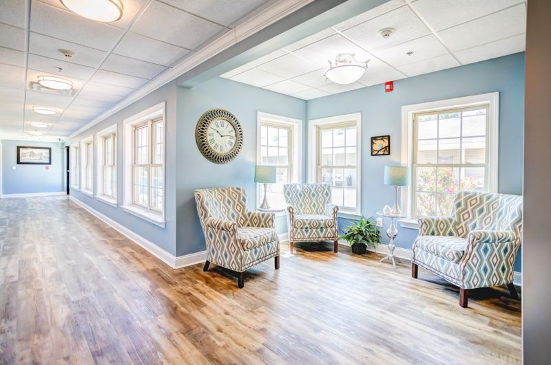 A long hallway with chairs and a clock on the wall.