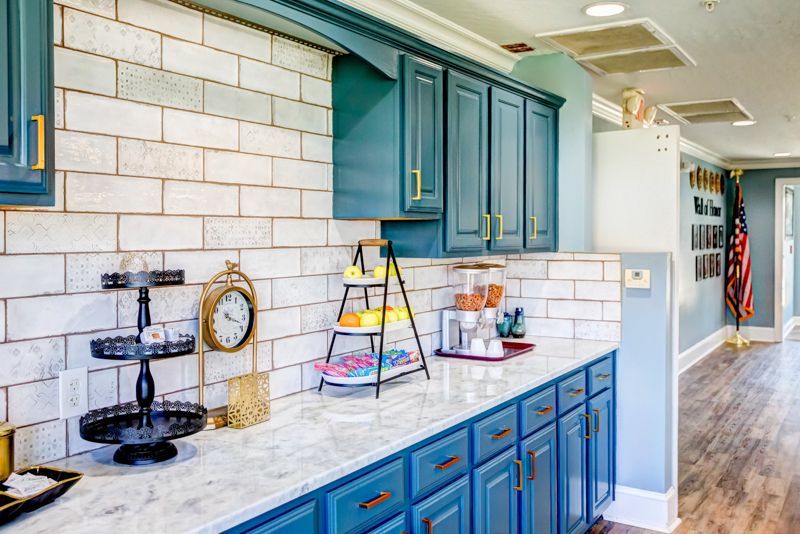 A kitchen with blue cabinets and a clock on the counter.