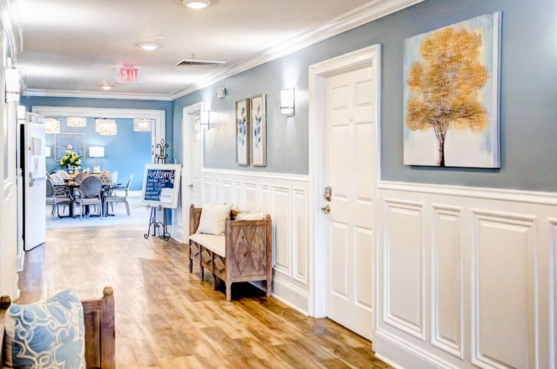 A long hallway with wooden floors and a painting of a tree on the wall.
