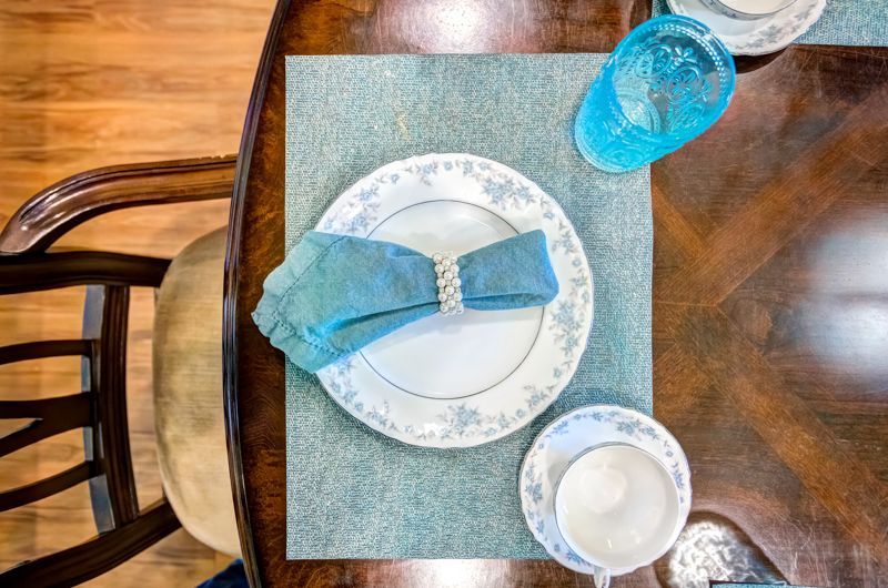A dining table with plates , cups , and glasses on it.