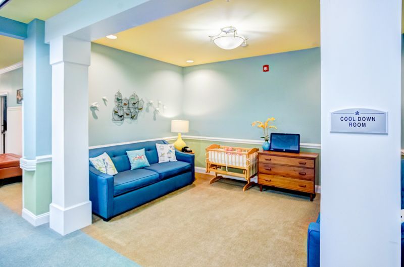 A living room with a blue couch and a crib.