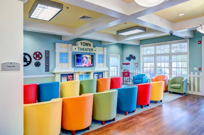A room with a lot of colorful chairs and a television on the wall.