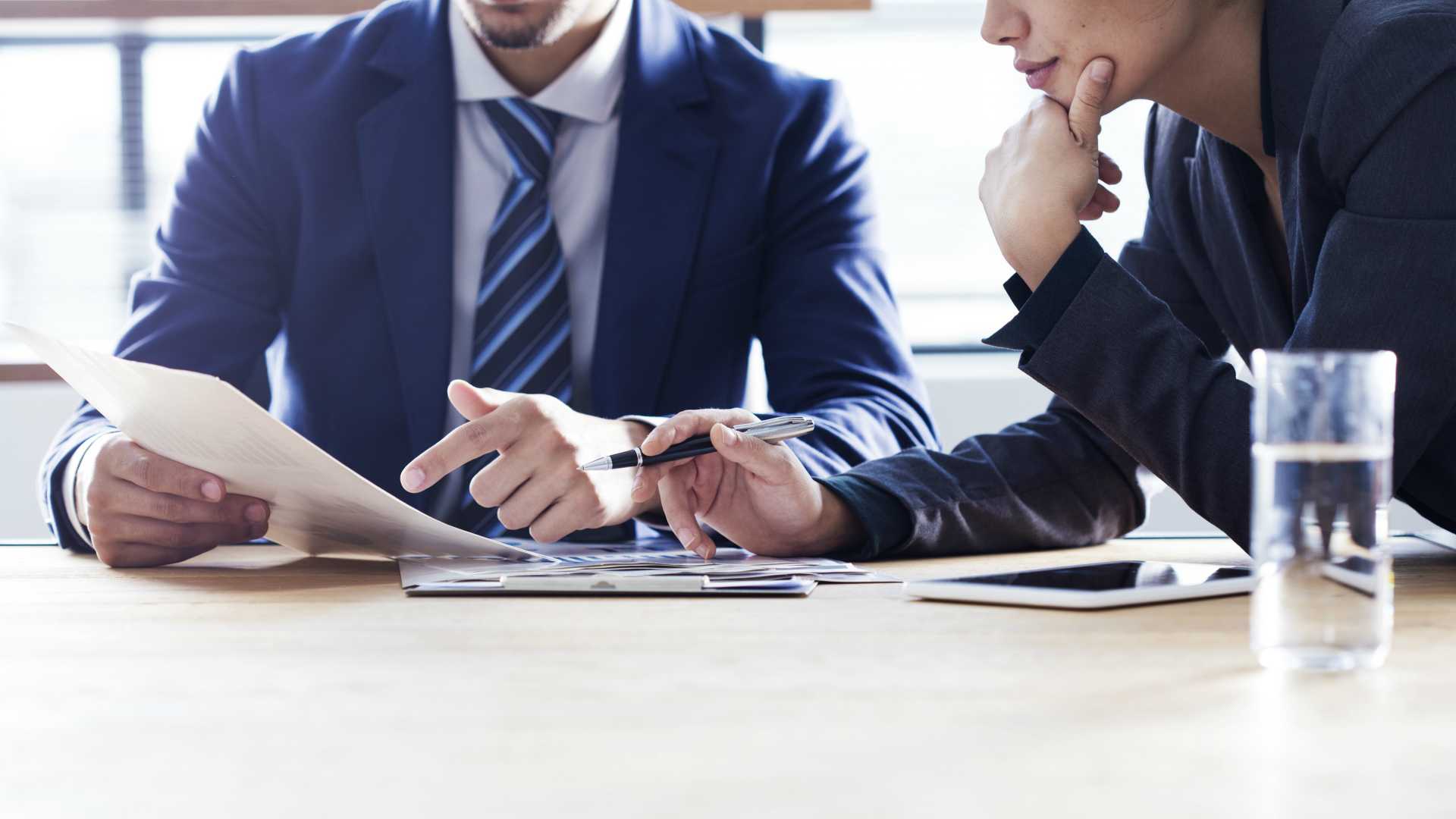 A man and a woman are sitting at a table looking at a piece of paper.