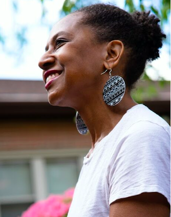 A woman wearing a white shirt and earrings is smiling.
