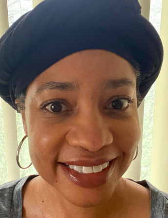 A woman wearing a black hat and earrings is smiling for the camera.