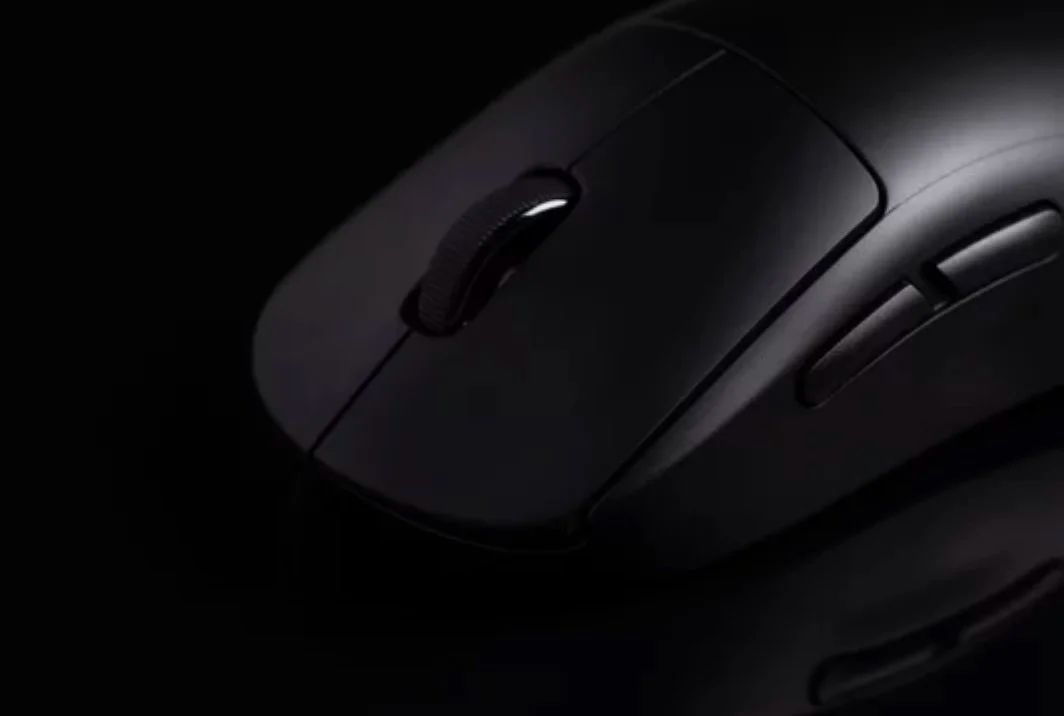 Black wireless computer mouse on a dark surface, with visible scroll wheel and side buttons.
