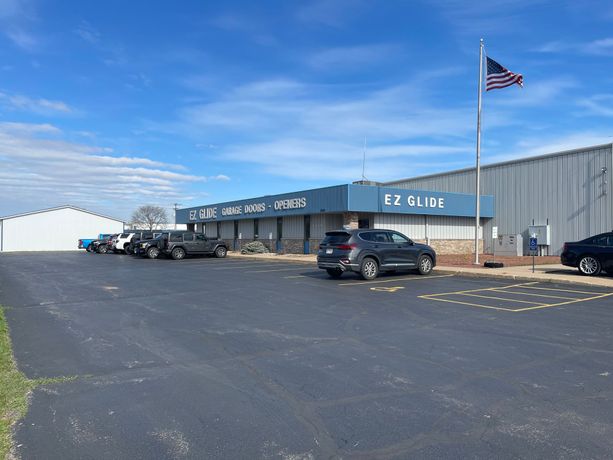 Industrial building with parked cars and an American flag under a clear blue sky