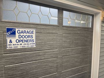 Gray garage door with a Garage Doors & Openers sign near the top left.