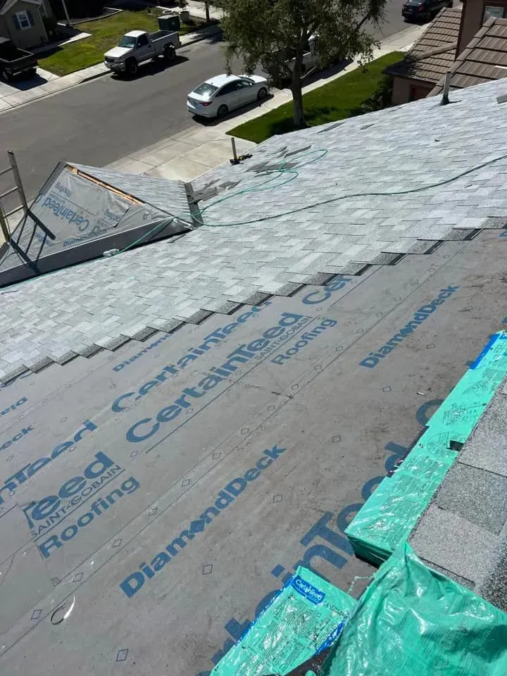 A roof with a lot of shingles and a green tarp on it.