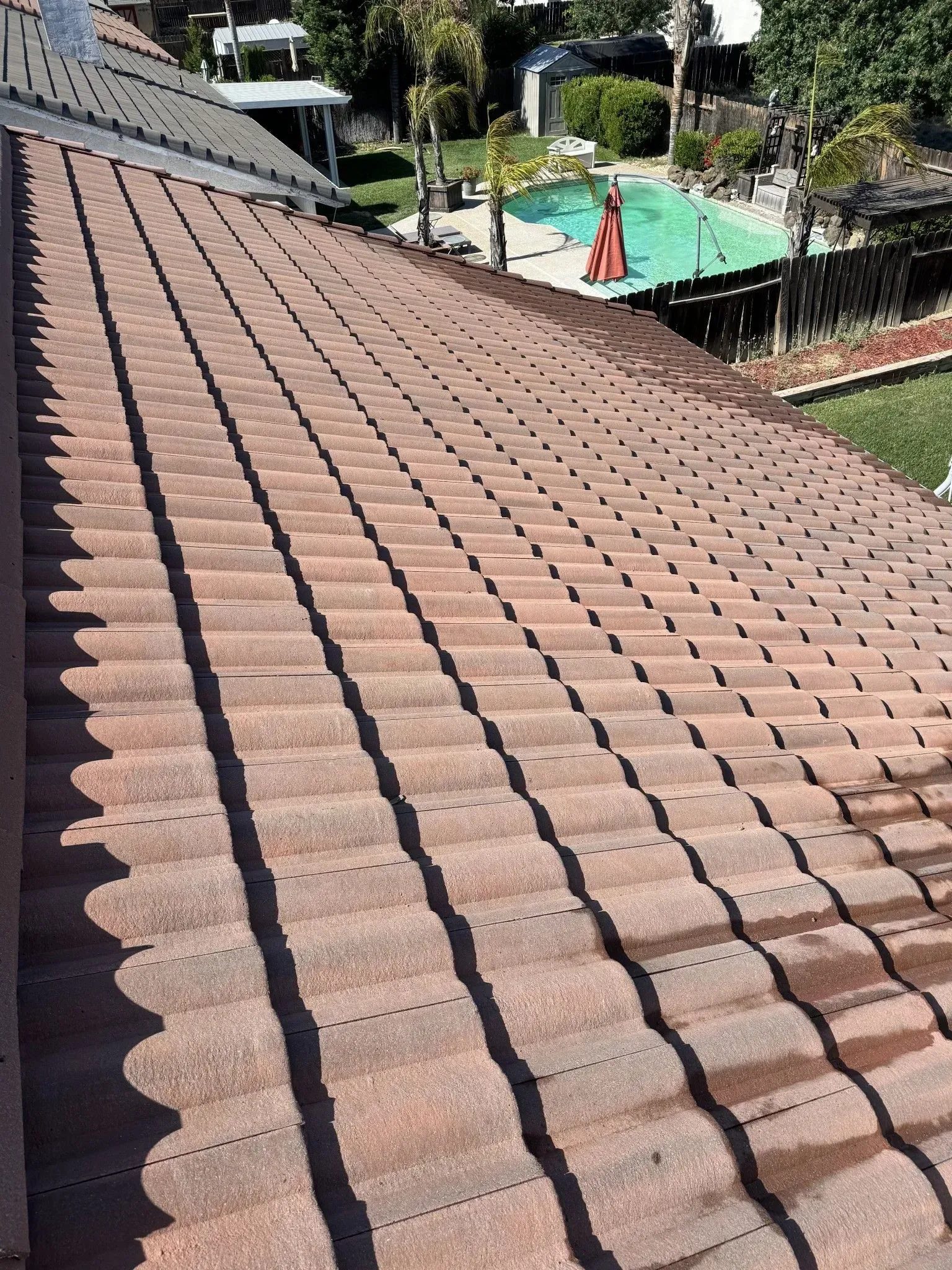 The roof of a house with a pool in the background.