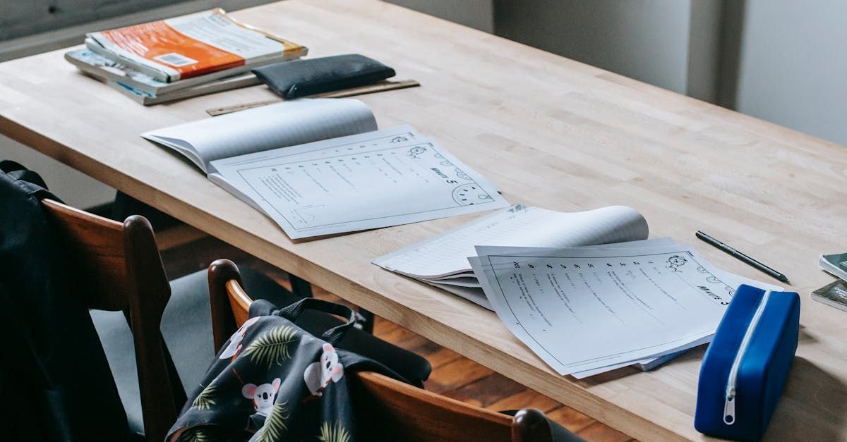 Un bureau avec des cahiers ouverts, des feuilles de papier, un stylo, 
