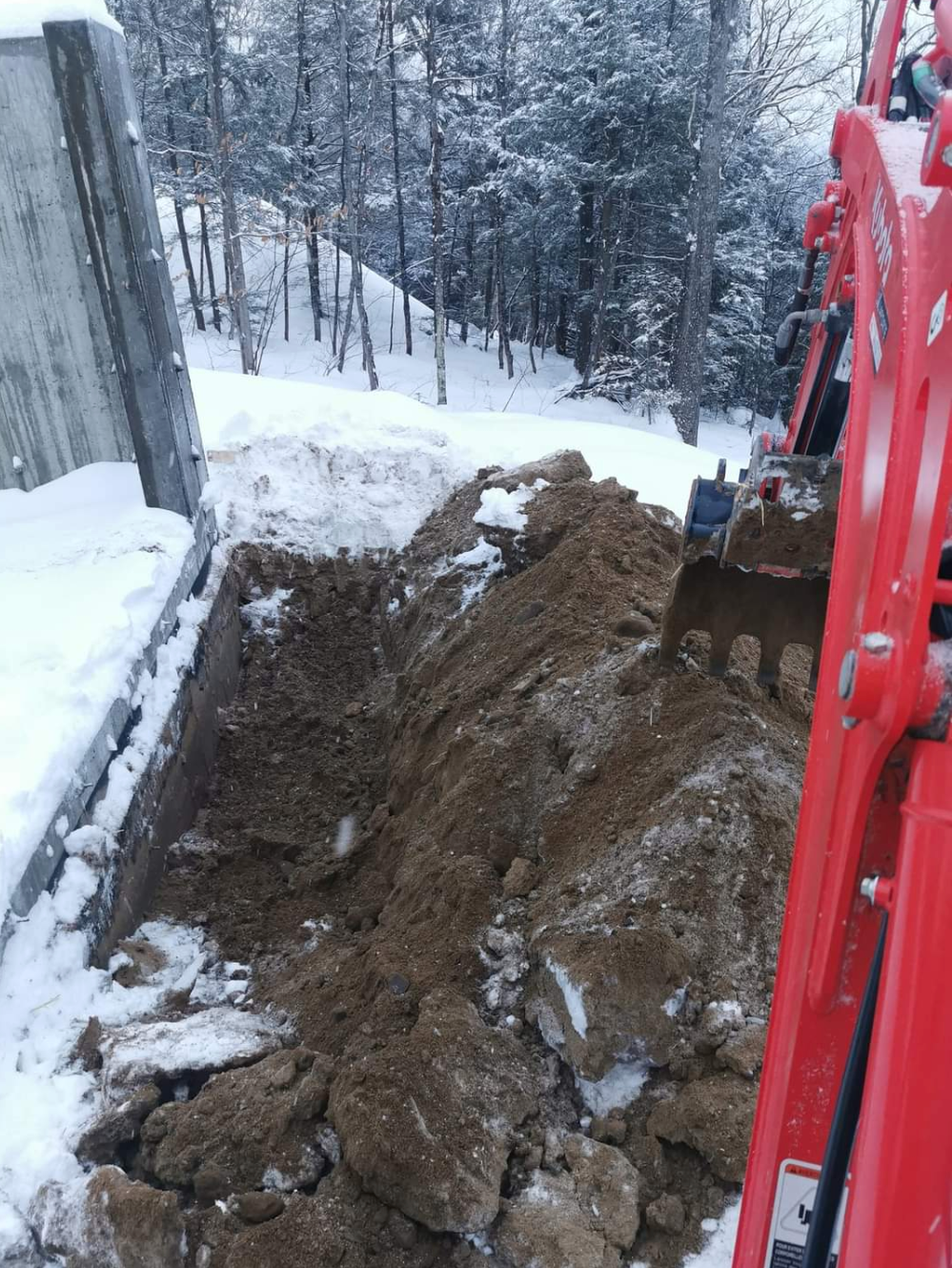 Une pelle rouge creuse un trou dans la neige.