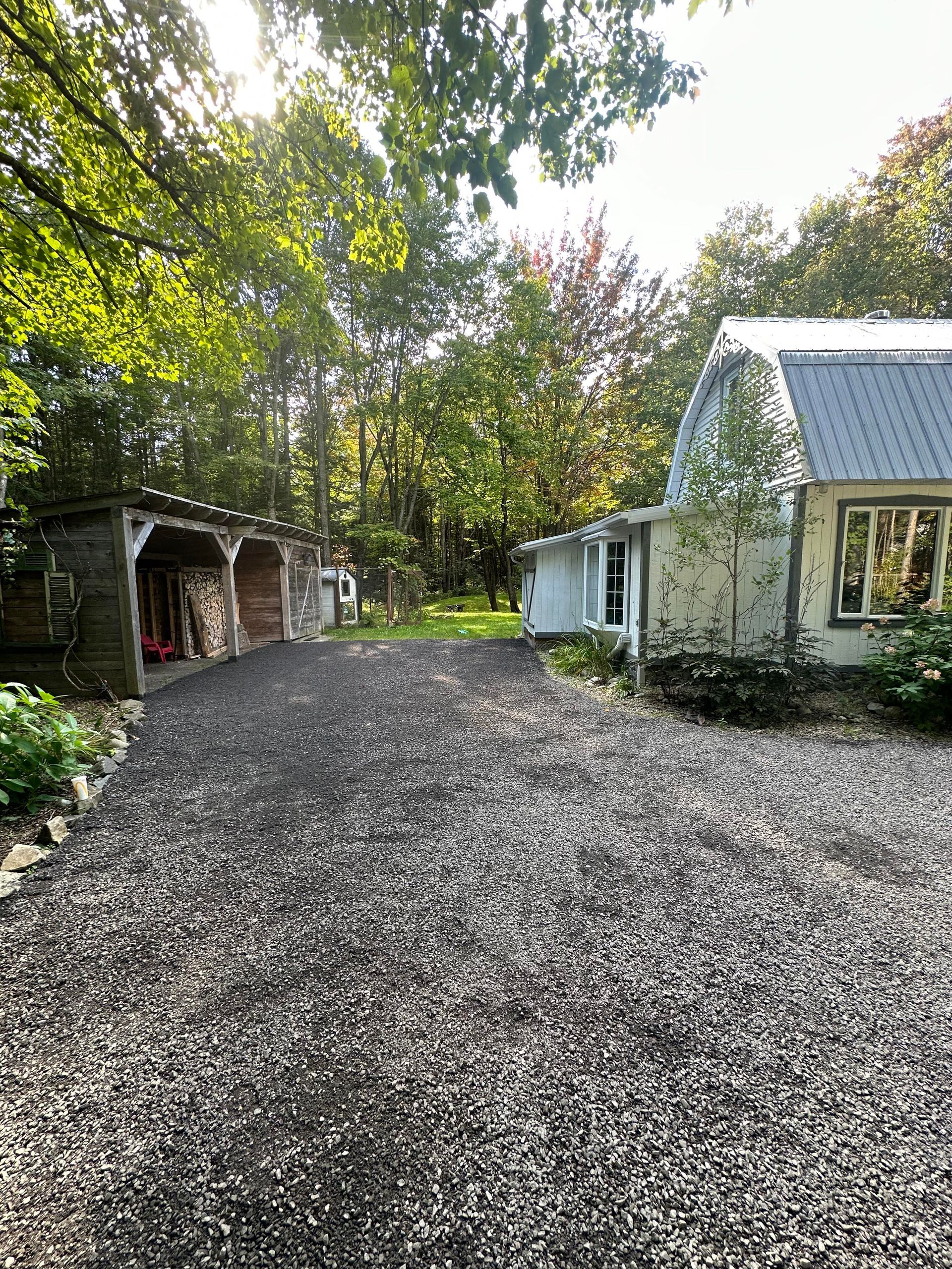 Une allée de gravier menant à une maison dans les bois.