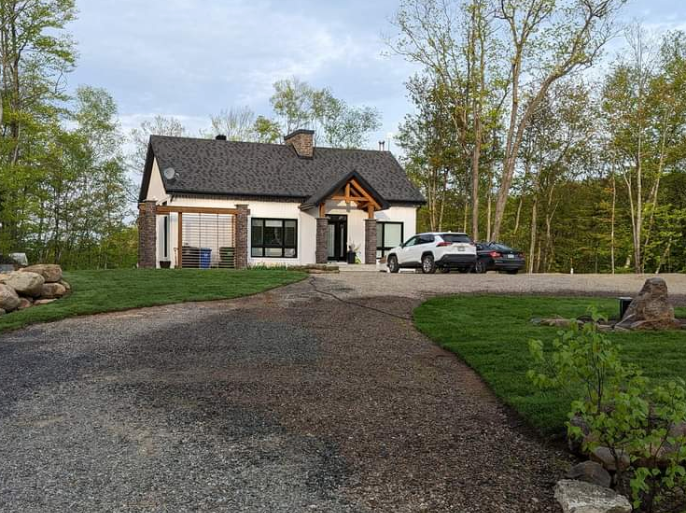 Une voiture est garée devant une maison dans les bois.