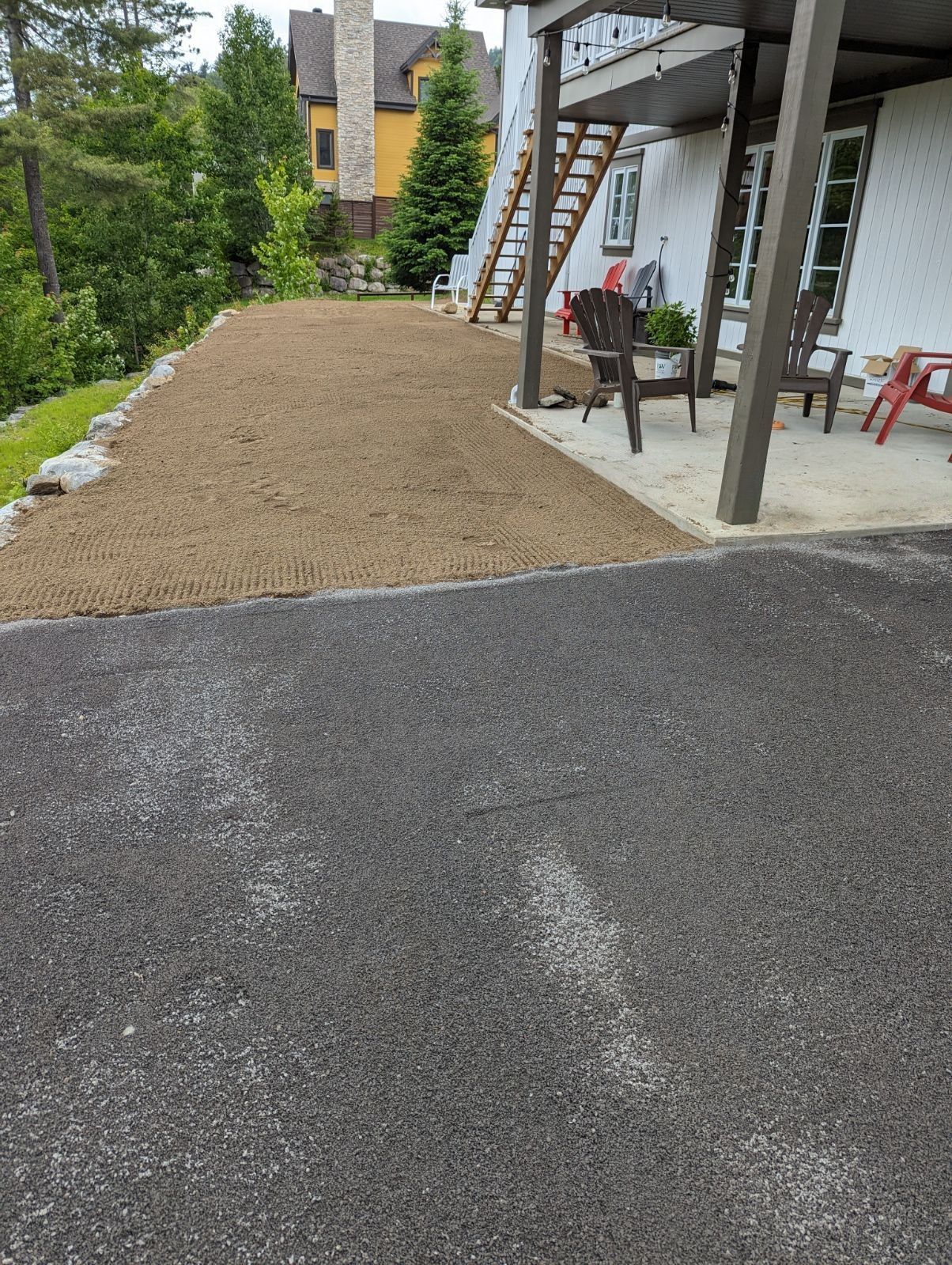 Une allée menant à une maison avec terrasse et chaises.