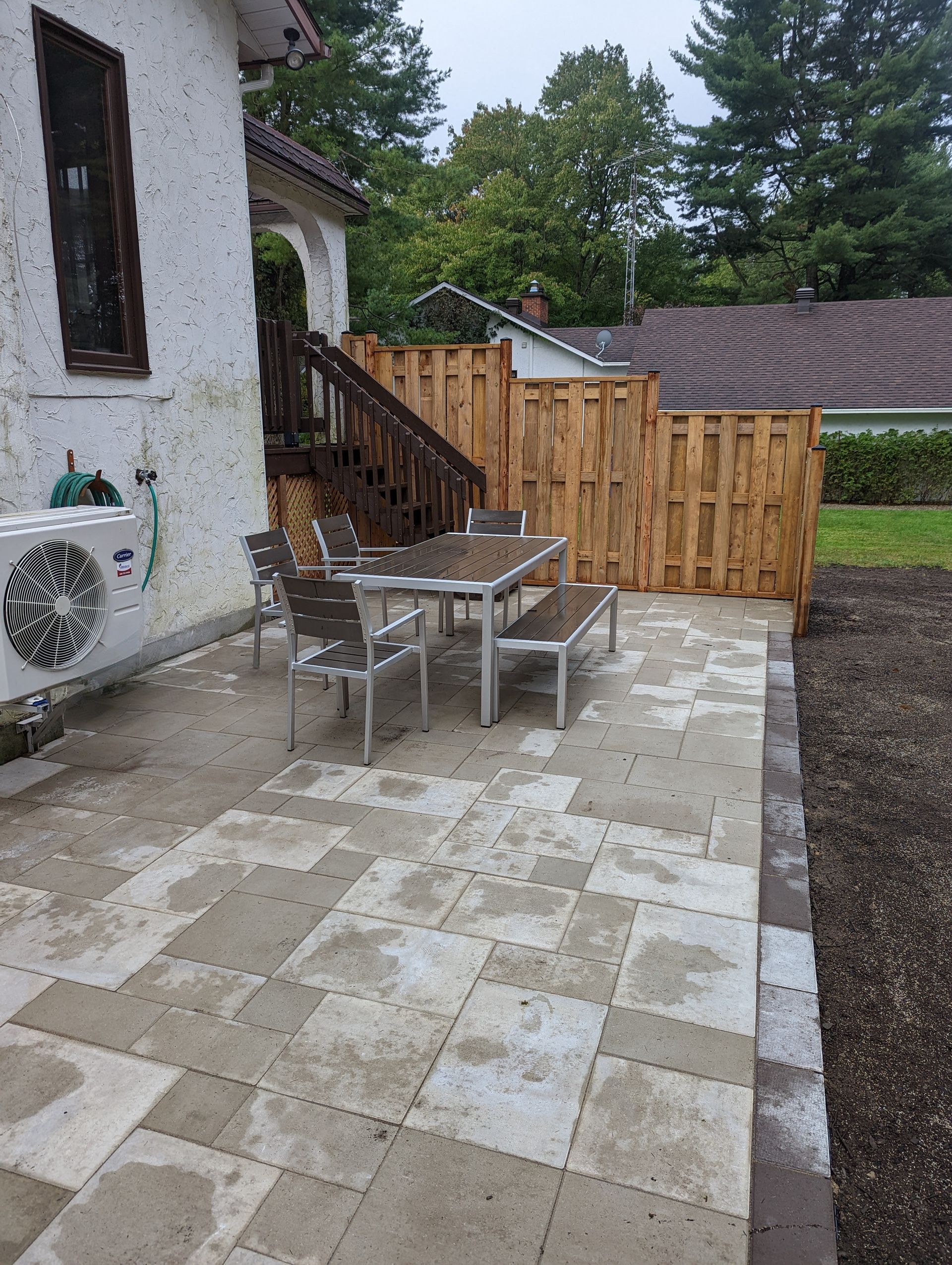 Un patio avec une table et des chaises devant une maison.