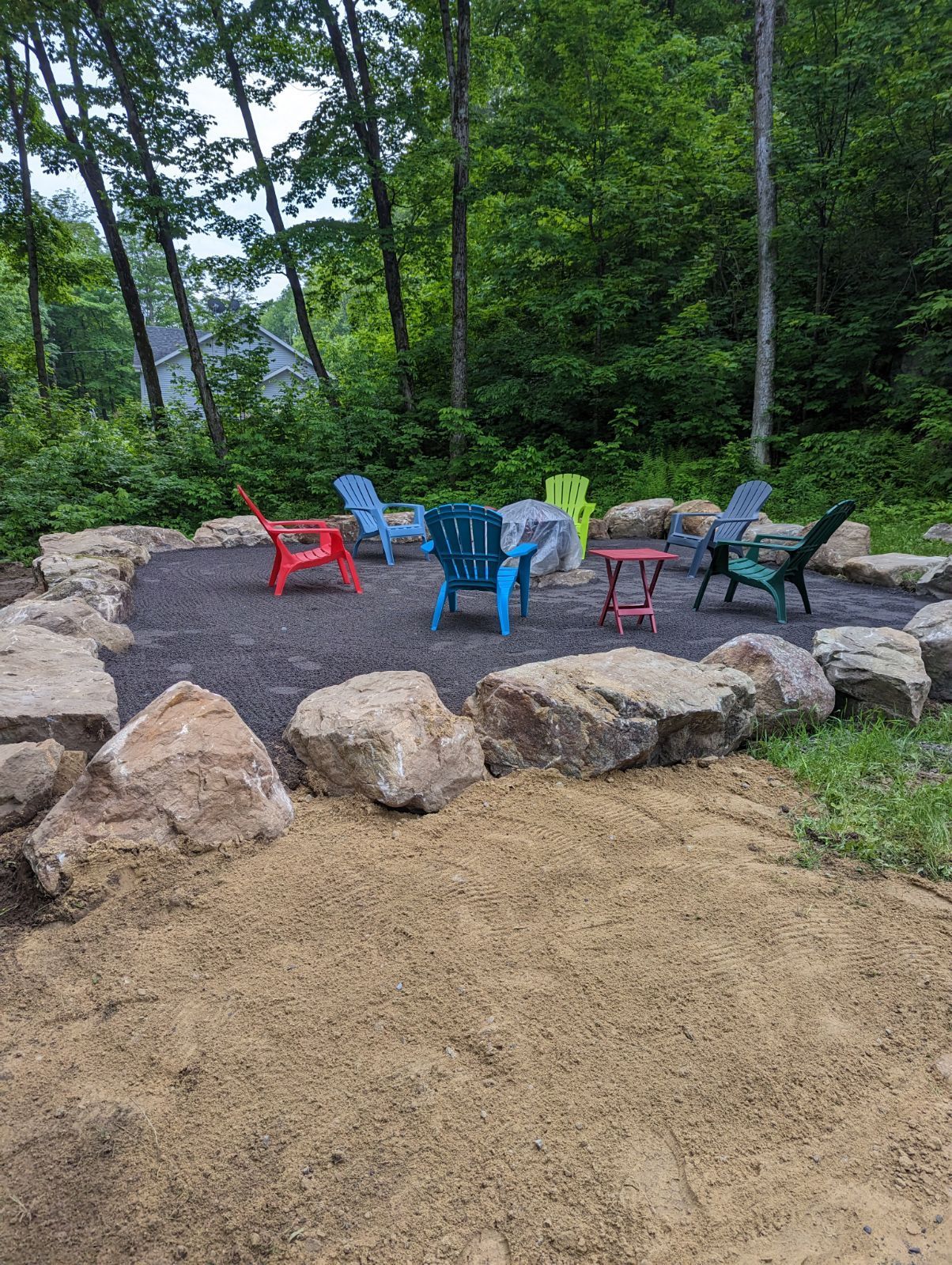 Un groupe de chaises de jardin est assis autour d'un foyer entouré de rochers.
