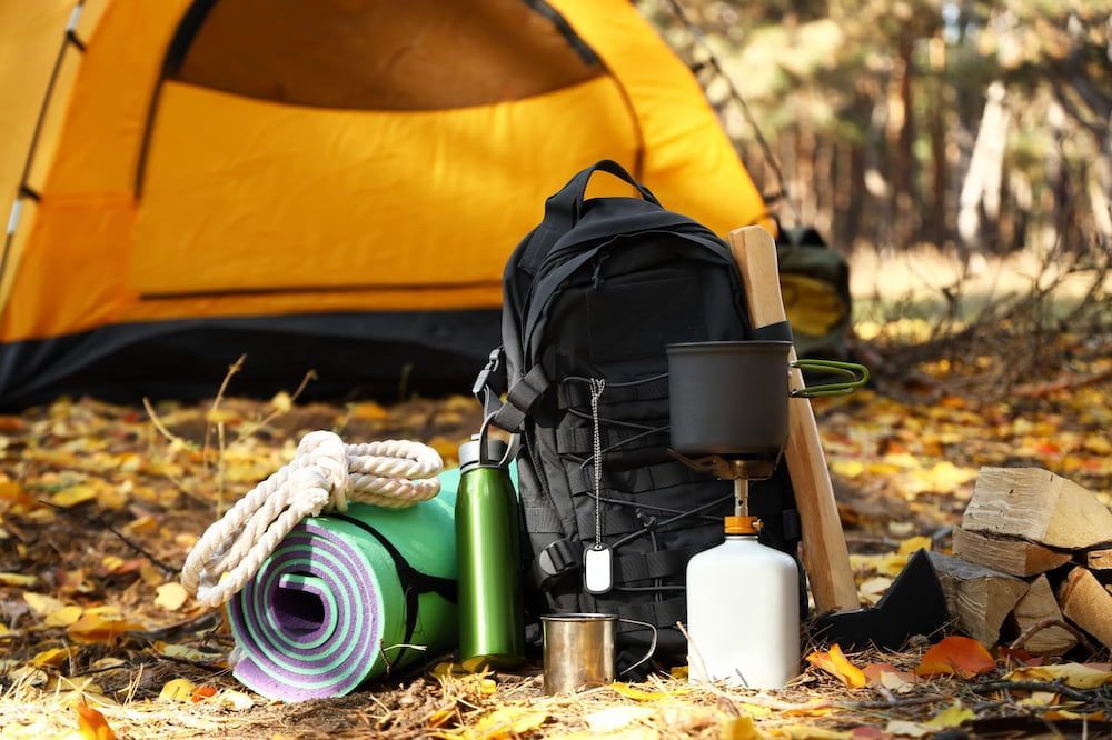 There is a Tent in the Background and a Backpack With Camping Equipment on the Ground — West End Cash Store In Proserpine, QLD