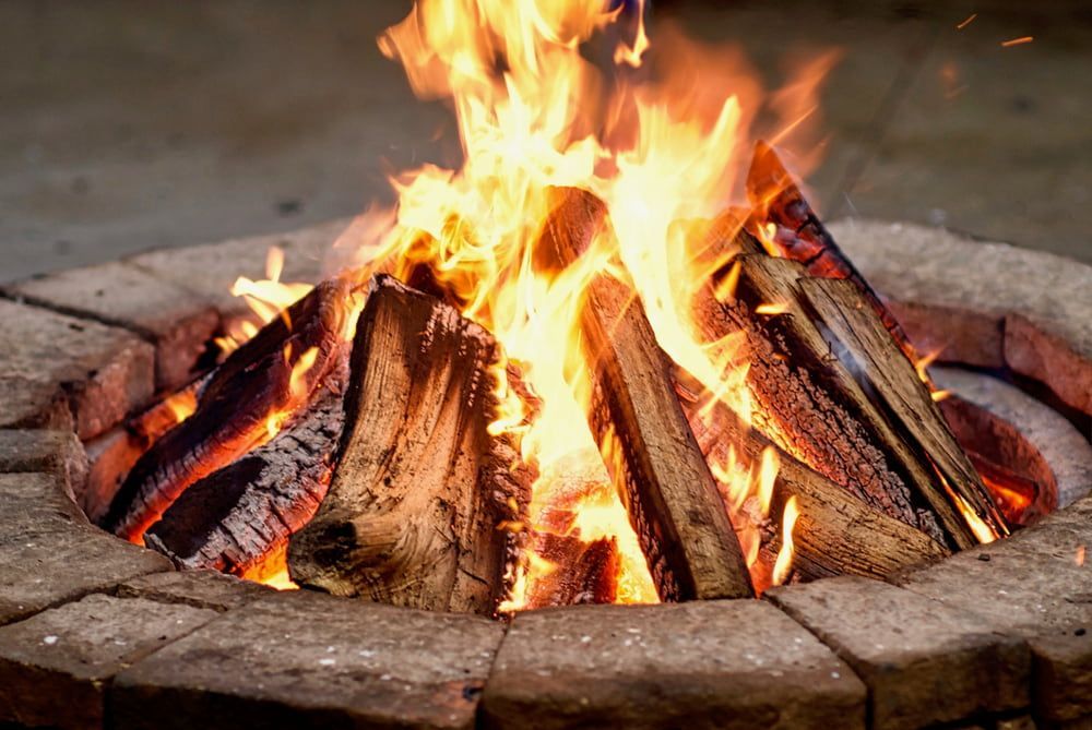 A Fire Pit With Logs Burning Brightly, Surrounded by a Cozy Outdoor Setting — West End Cash Store In Proserpine, QLD